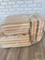 Stacked set of six striped patio cushions wrapped in plastic