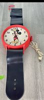 Front view of Elgin Mickey Mouse wristwatch-style wall clock showing case, dial, strap and power cord