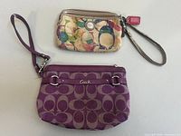 Both Coach wristlets side by side showing overall design and wrist straps