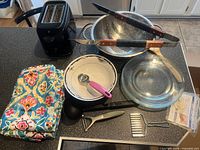 Group shot of all items on counter including toaster, colander, utensils, tablecloth, glass plates