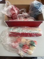 Overview of shoebox containing assorted pillar candles and separate bags with taper and novelty candles