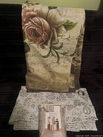 All three fabric items displayed: packaged curtain panel, unwrapped leaf panel with grommets, folded rose print shower curtain