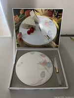 Open box showing plate, cheese knife and illustrated insert