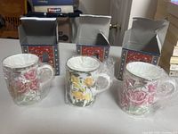 Three wrapped floral mugs with open individual boxes