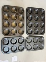 Top view of four pans: two 6-cup non-stick, one 12-cup non-stick, one worn 12-cup Tala