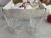 Two of the eight crystal wine glasses displayed in front of packing box