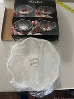 Box and wrapped chrome-plated wire basket on table with tape for scale