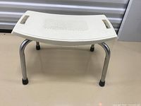 Front view of curved plastic shower stool with chrome legs and rubber feet