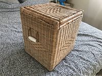 Closed wicker hamper showing woven sides and handle