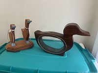 Group shot of both wooden duck items on bin lid