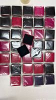 Overview of 30 boxed items arranged on table showing black and pink colours