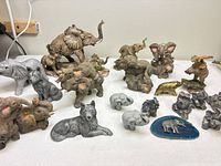 Overview of assorted elephant figurines, wolf, crocodile and agate slice on tabletop