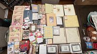 Overhead of assorted paper pads, card kits, notebooks, journals, boxed frames, twine and punch