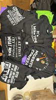 Loose display of several slogan t-shirts showing designs and tags