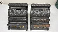 front view pair cast iron cash register banks showing decoration and lettering