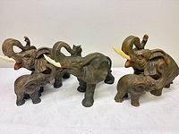 Group of five brown resin elephant figurines: three adults, two calves