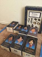 All boxed Fontanini musician figurines and the box of musical instruments together on carpeted floor, showing box artwork and condition.