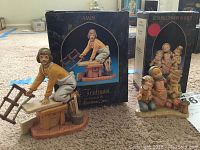 Photo of the Amos figurine beside its original box showing the name and illustration