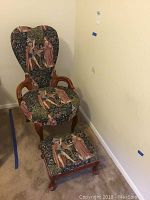 Full view of vintage chair with matching stool placed in corner on carpeted floor. Shows dimensions and overall condition including fabric print and wood frame.