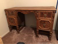 Full front view of vintage wooden desk showing three drawers and carved decorative details