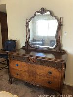 Front view of vintage wooden dresser with attached mirror showing drawers and ornate wood details