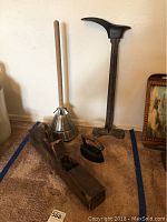 Photo showing antique wooden hand plane tool, shoe mold, metal plunger with wooden handle, and vintage iron.