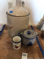 Front view of all three pottery pieces: large jug, covered pot, and small jar