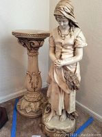 Full view of the statue and matching pedestal placed on carpet against a white wall, showing size and styling.