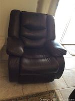 Front view of dark brown leather recliner showing cushioned seat, backrest, and armrests.