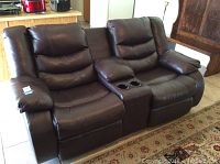 Full front view of dark brown leather reclining loveseat with two seats and center console with cupholders