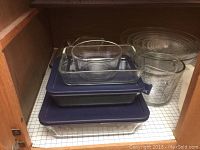Stack of glass baking dishes and metal bowls inside cabinet
