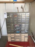Plastic storage cabinet with many small clear drawers containing assorted hardware