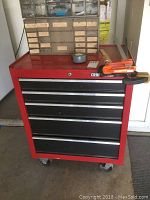 Front view of red and black 5 drawer Craftsman tool cabinet with items placed on top.
