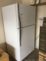 White Hot Point refrigerator with freezer on top seen from front and side, showing exterior and handles.