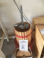 Front view of wooden fruit and wine press with instruction manual and base stand