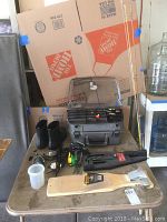 Full lot on table showing fishing rods, boots, tackle box, spooling station, reels, knives, and measuring board