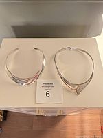 Two sterling silver collar chokers on display