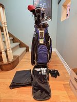 Full view of carry bag loaded with clubs, accessory bag open showing contents, gloves and shoe bag on floor
