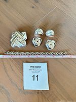 Group view of bracelet, brooch, two earring pairs with measuring tape