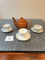 Full lot showing teapot and three teacup/saucer combinations