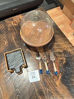 Group view of wood cheese board with glass cloche, coaster holder, three cheese knives