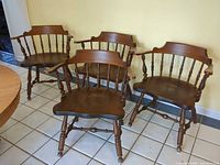 Four matching wooden spindle-back armchairs grouped together