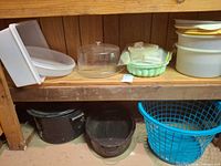 Shelf with Tupperware keepers, gelatin mold, nesting bowls; enamel pots and blue basket below