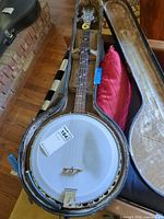 Full view of banjo in open case showing head, neck, and hardware