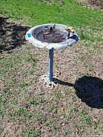 Full view of metal bird bath standing on lawn