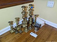 Group view of eight brass candlesticks, silvertone cup and box with candles