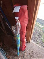 Full view of chair in bag and umbrella leaning in shed