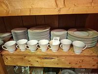Front view showing stacks of dinner plates, salad plates and cups on shelf