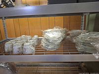 wrapped teacups and stacks of plates on metal shelf