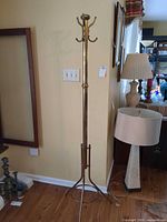 Full view of brass tone coat tree standing in room